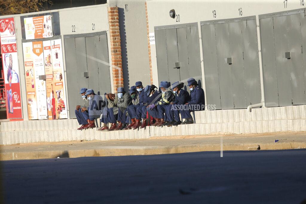 Tsvangirayi Mukwazhi Zimbabwean police take a break at the side of a street in Harare, Friday, July, 31, 2020. Zimbabwe's capital, Harare, was deserted Friday, as security agents vigorously enforced the country's lockdown amidst planned protests. Police and soldiers manned checkpoints and ordered people seeking to get into the city for work and other chores to return home. (AP Photo/Tsvangirayi Mukwazhi)