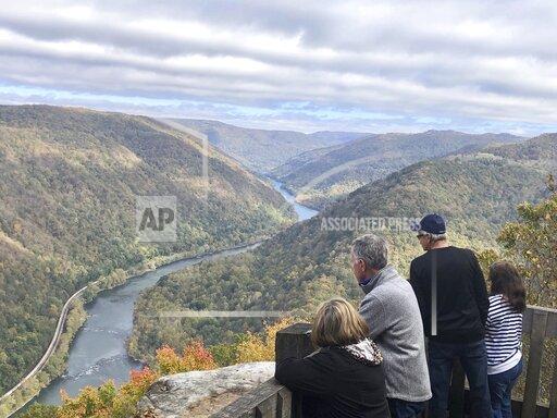 Visitors look down on the New River Gorge from a national park overlook Wednesday, Oct. 27, 2021, in Grandview, W.Va. Under legislation passed by Congress in 2020, some of America's most spectacular natural settings are getting a makeover. Historic masonry grills have been restored near the Grandview Visitor Center. (AP Photo/John Raby)