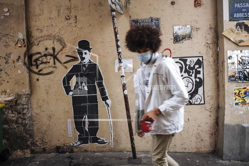 Lewis Joly A man wearing a face mask, walks by a Charlie Chaplin street art, in the Montmartre district of Paris, Sunday Oct.25, 2020. A curfew intended to curb the spiraling spread of the coronavirus, has been imposed in many regions of France including Paris and its suburbs. (AP Photo/Lewis Joly)