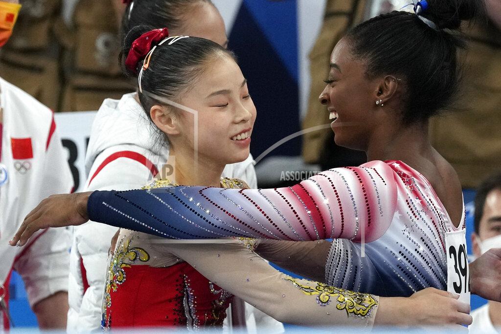 Gregory Bull Gold medalist Guan Chenchen, of China, left, gets a hug from bronze medalist Simone Biles, of the United States, after performing on the balance beam during the artistic gymnastics women's apparatus final at the 2020 Summer Olympics, Tuesday, Aug. 3, 2021, in Tokyo, Japan. (AP Photo/Gregory Bull)