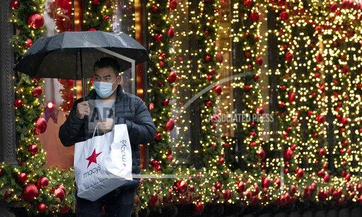FILE - In this Nov. 30, 2020 file photo, a shopper walks by a holiday window display in New York. Factoring holiday expenses into your budget all year long is effective for avoiding debt, but it’s not always feasible with a limited budget or unforeseen expenses. When that’s the case, lacking a strategy for holiday spending can leave you vulnerable to debt and overspending that delays financial goals. But it’s not too late to come up with a last-minute plan to save money for the holidays. (AP Photo/Mark Lennihan, File)