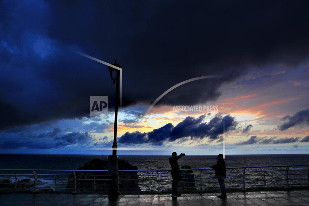 Hussein Malla Storm clouds move in at sunset as people take pictures, in Beirut, Lebanon, Tuesday, Feb. 16, 2021. (AP Photo/Hussein Malla)