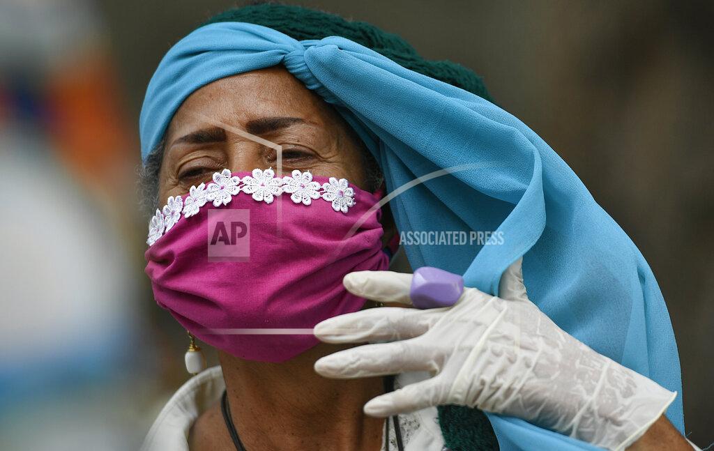 An elderly woman wearing a protective face mask and disposable gloves as a precaution against the spread of the new coronavirus, adjusts her headscarf as she takes a walk outside, breathing in fresh outdoor air, on the grounds of a nursing home in Caracas, Venezuela, Saturday, May 2, 2020. Venezuela's government allowed elderly people and children to go outdoors for a few hours, relaxing a strict quarantine to help curb COVID-19. (AP Photo/Matias Delacroix)