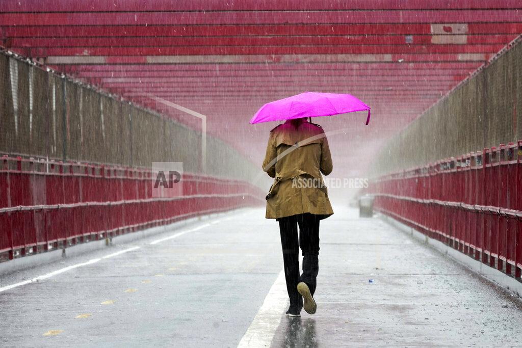 Mary Altaffer A pedestrian walks during a heavy downpour of rain over the Williamsburg bridge, Tuesday, Oct. 26, 2021, in New York. A flash flood watch is in effect as a nor'easter moves through the New York metro area. (AP Photo/Mary Altaffer)