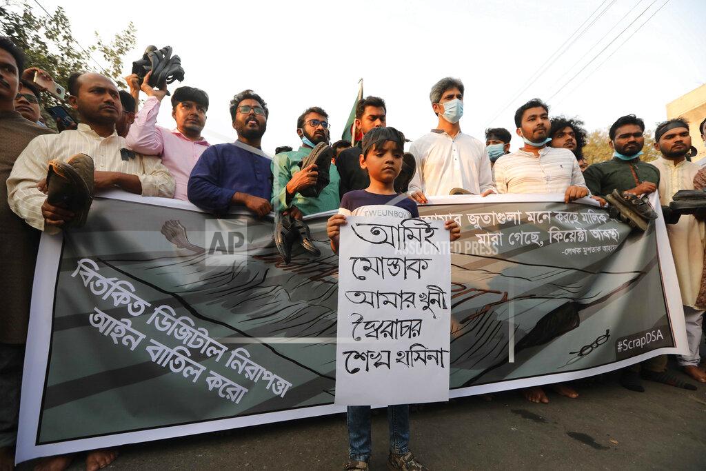 Mahmud Hossain Opu A boy joins adults during a demonstration against the death in prison of a writer who was arrested on charges of violating the sweeping digital security, in Dhaka, Bangladesh, Friday, Feb. 26, 2021. Mushtaq Ahmed, 53, was arrested in Dhaka in May last year for making comments on social media that criticized the Prime Minister Sheikh Hasina government's handling of the coronavirus pandemic. He had been denied bail at least six times. The poster reads "I am Mushtaq and autocrat Sheikh Hasina is my killer." (AP Photo/Mahmud Hossain Opu)
