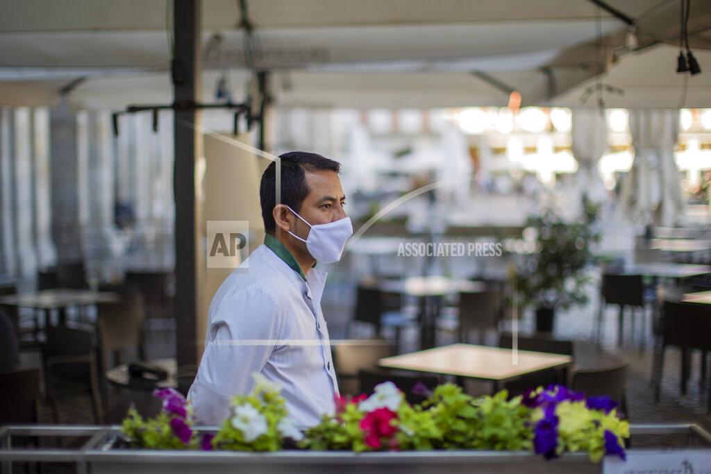 Manu Fernandez A waiter wearing a face mask to prevent the spread of coronavirus waits for customers in downtown Madrid, Spain, Friday, Oct. 9, 2020. Spanish Prime Minister Pedro Sánchez is holding a Cabinet meeting to consider declaring a state of emergency for Madrid in order to impose stronger anti-virus restrictions on reluctant regional authorities. (AP Photo/Manu Fernandez)