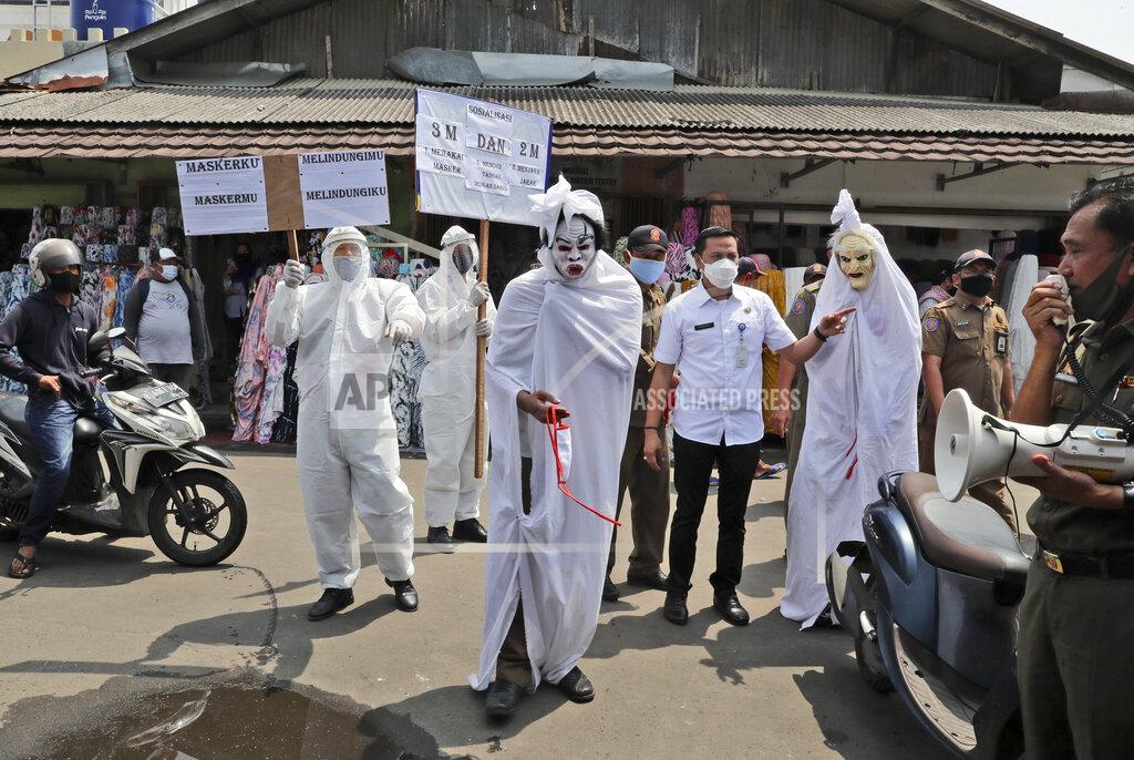 Tatan Syuflana Government officials dressed as a shrouded ghosts, traditionally known as a 'pocong', to represent the victims of COVID-19, take part in a coronavirus awareness campaign at a market in Tangerang, Indonesia, Wednesday, Sept. 16, 2020. Writings on the posters read "My mask protects you, your mask protects me" and "Wear mask, wash your hands, keep your distance". (AP Photo/Tatan Syuflana)