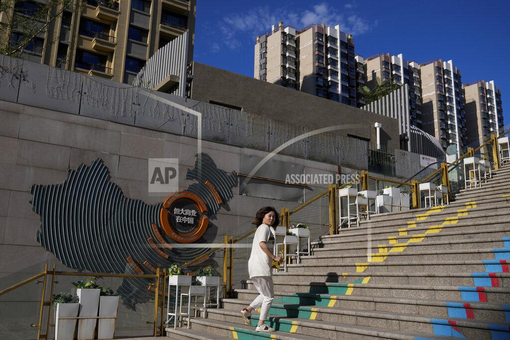 Andy Wong A woman looks back as she walks by a map showing Evergrande development projects with its apartment buildings seen behind, at an Evergrande city plaza in Beijing, Tuesday, Sept. 21, 2021. Global investors are watching nervously as the Evergrande Group, one of China's biggest real estate developers, struggles to avoid defaulting on tens of billions of dollars of debt, fueling fears of possible wider shock waves for the Chinese financial system. (AP Photo/Andy Wong)