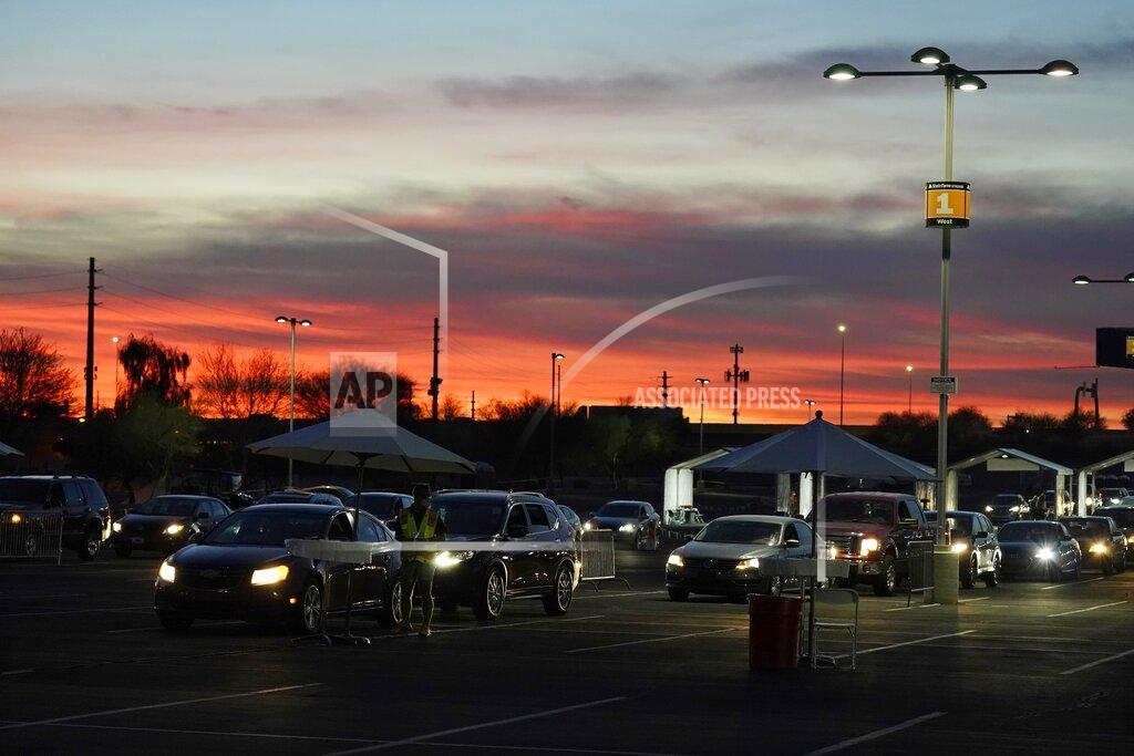 FILE - In this Jan. 12, 2021, file photo, vehicles line up so people can get their COVID-19 vaccination cards after being vaccinated in a pre-registered drive-thru in the parking lot of the State Farm Stadium in Glendale, Ariz. Arizona reported 4,748 additional known COVID-19 cases and 209 deaths on Tuesday, Jan. 26 the one-year anniversary of the announcement of the state's first confirmed coronavirus case in the outbreak that has since claimed thousands of lives statewide. (AP Photo/Ross D. Franklin, File)