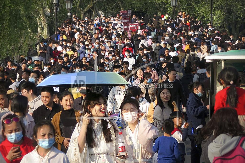 Mark Schiefelbein Visitors wearing face masks to protect against COVID-19 walk across a causeway at the West Lake in Hangzhou in eastern China's Zhejiang Province, Sunday, April 4, 2021. Domestic tourists were out in force at some of China's most popular tourist sites on a holiday weekend as the country continues to report few new cases of coronavirus within its borders. (AP Photo/Mark Schiefelbein)