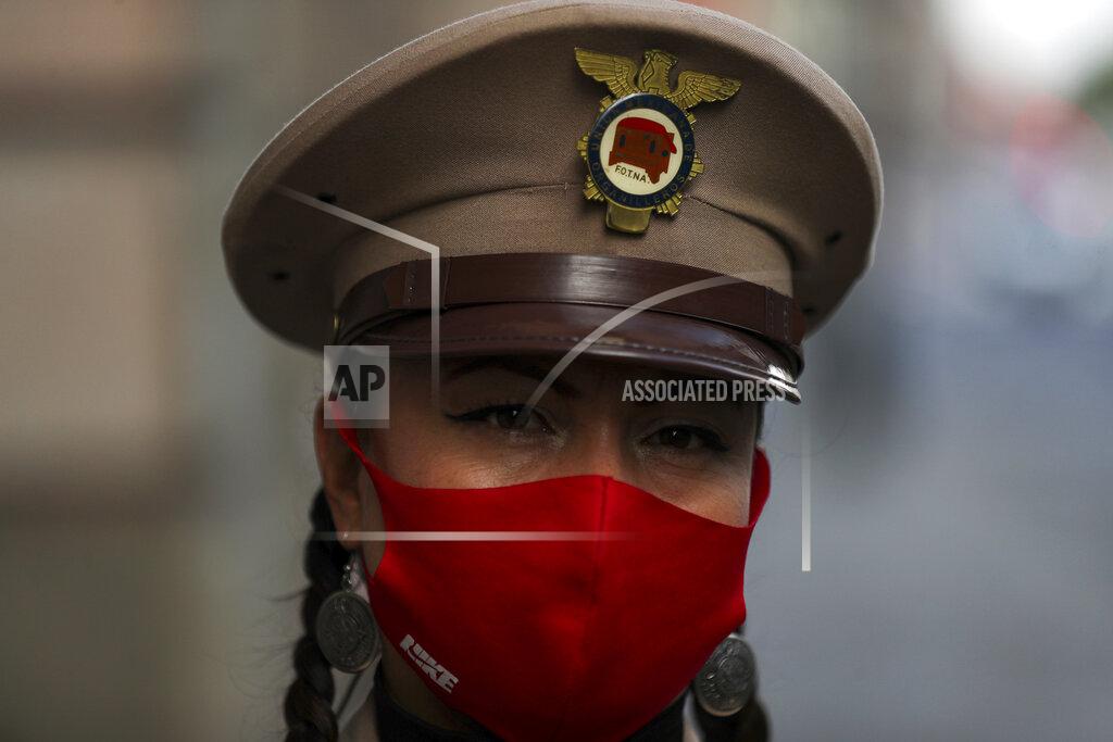 Fernando Llano An organ grinder, wearing a protective face mask, eyes the camera as she waits for a delivery of donated groceries, in Mexico City, Thursday, June 4, 2020. CADENA, a non-profit organization dedicated to assisting during emergencies and disasters around the world, dispatched groceries to hundreds of organ grinders who play for tips from passersby but have lost their source of income due to restrictions amid the new coronavirus. (AP Photo/Fernando Llano)