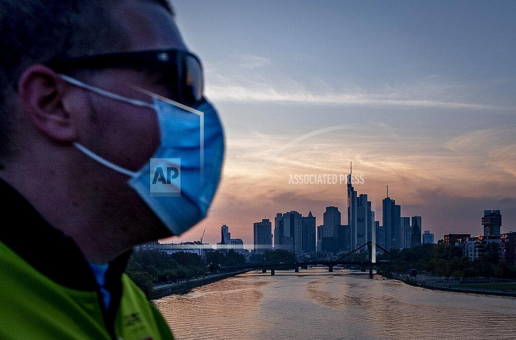 A man wears a face mask as he walks across the bridge over the river Main in Frankfurt, Germany, Wednesday, Sept. 30, 2020. (AP Photo/Michael Probst)
