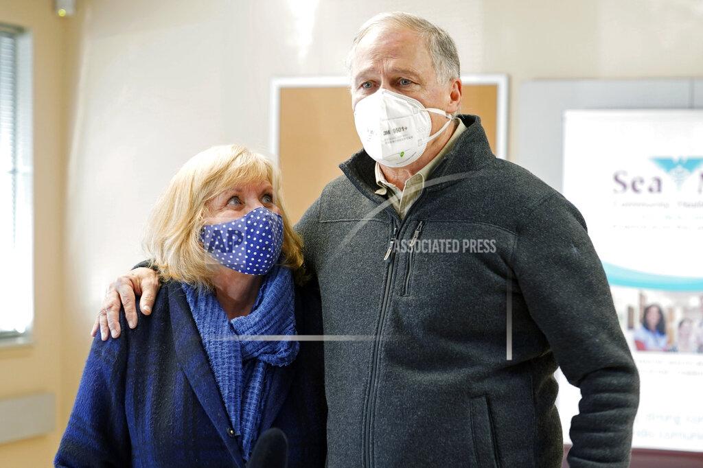 Ted S. Warren Washington Gov. Jay Inslee stands with his wife Trudi as they talk to reporters after they both were given the first shot of the Moderna COVID-19 vaccine, Friday, Jan. 22, 2021, at a Sea Mar Community Health Center in Olympia, Wash. (AP Photo/Ted S. Warren)