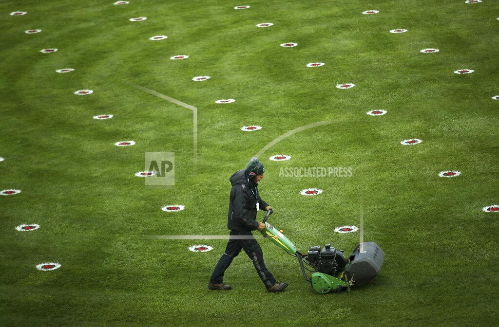 Tim Goode A member of the grounds staff cuts the grass dotted with social distance markers in the parade ring before the start of the Liverpool NHS Day of the 2021 Grand National Festival at Aintree Racecourse in Liverpool, England, Thursday April 8, 2021. The Aintree Grand National 2021 is a the three day festival of horse racing first run in 1839.(Tim Goode/PA via AP)