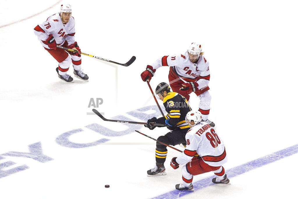 Chris Young Boston Bruins' Charlie Coyle (13) moves the puck between Carolina Hurricanes' Teuvo Teravainen (86) and Jordan Staal (11) as Hurricanes' Brady Skjei (76) looks on during the third period of an NHL Eastern Conference Stanley Cup hockey playoff game in Toronto, Thursday, Aug. 13, 2020. (Chris Young/The Canadian Press via AP)