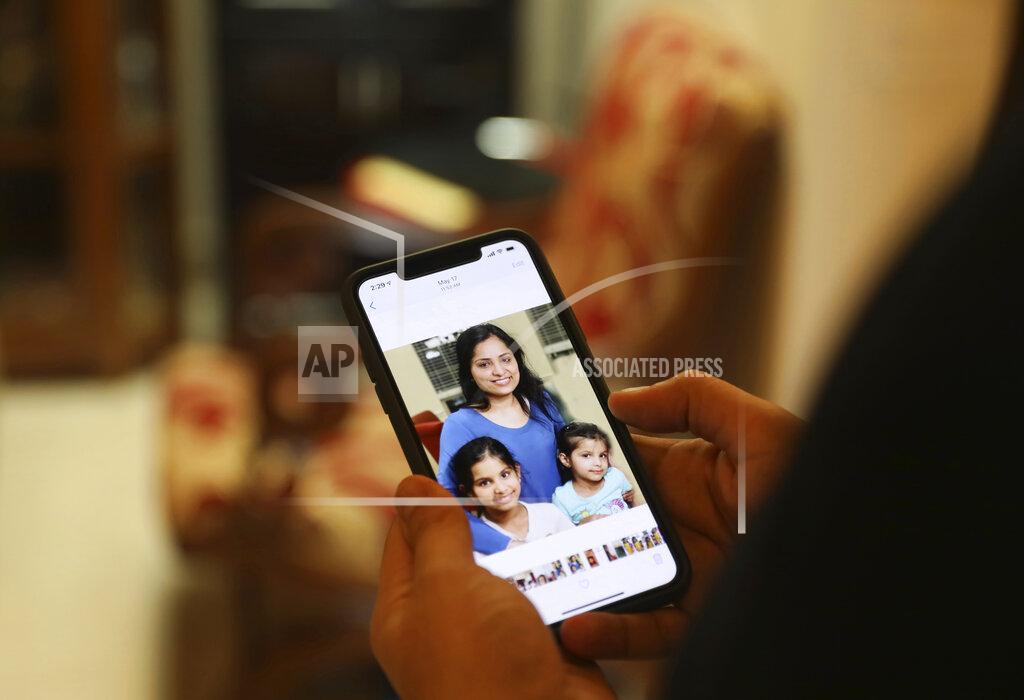 Manish Swarup Karan Murgai, an IT management consultant for a multinational based in Dallas, shows on his phone in New Delhi, India, a photograph of his family, who are in Dallas. Tuesday, June 30, 2020. Murgai, came to Delhi in March this year after his father died. Murgai and at least 1,000 others like him, whose U.S. visas are tied to their jobs in the U.S., are now stranded in India, after an executive order signed by President Donald Trump that suspends applications for H-1B and other high-skilled work visas from abroad. (AP Photo/Manish Swarup)