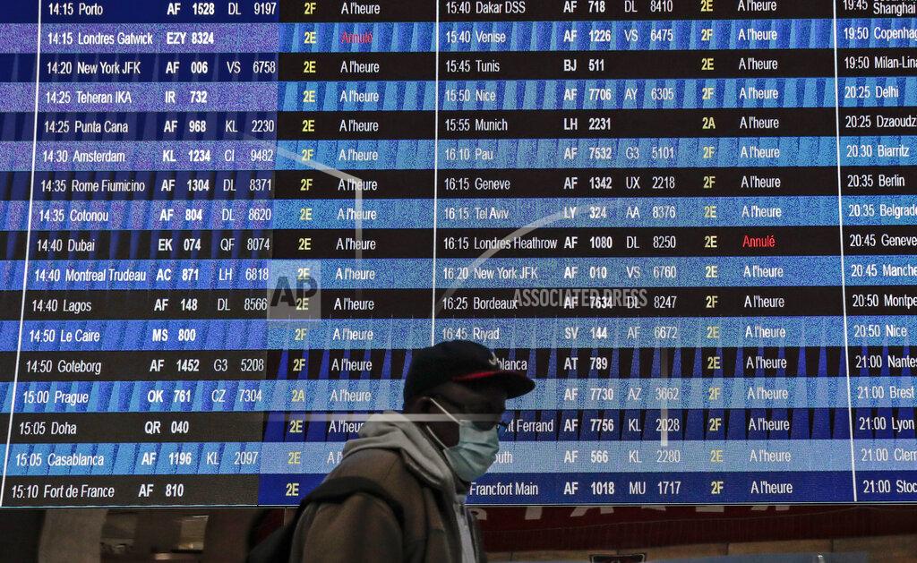 Lewis Joly Passenger wearing a face mask walk past a flight information board at Paris' Charles de Gaulle international airport in Roissy, Monday Dec. 21, 2020. France is banning all travel from the U.K. for 48 hours in an attempt to make sure that a new strain of the coronavirus in Britain doesn't reach its shores. (AP Photo/Lewis Joly)
