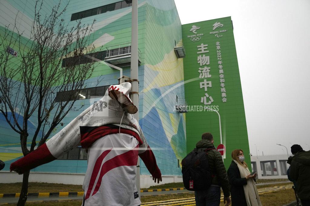 Ng Han Guan A journalist puts on a jacket outside the Main Distribution Center built to provide logistic support for the Beijing Winter Olympics and Paralympics in Beijing, China, Thursday, Dec. 9, 2021. The 34-meter-tall building has started operation at the end of last year to receive, store and distribute furniture, sport and technical equipment, and other materials for the current test events and next year's Winter Games. (AP Photo/Ng Han Guan)