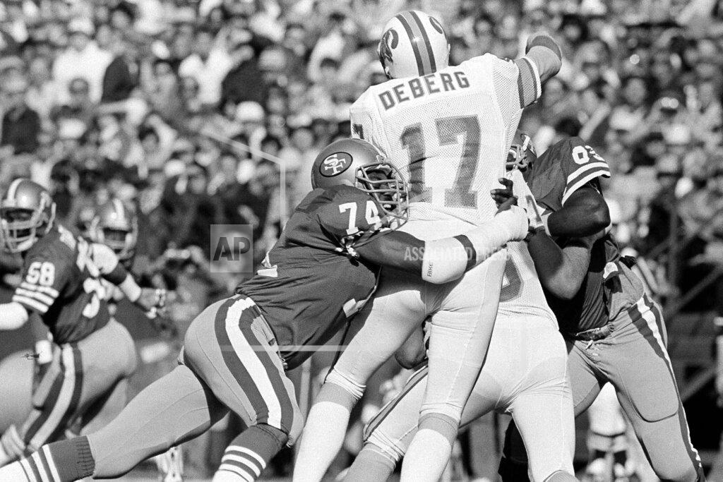 Eric Risberg FILE - In this Nov. 18, 1984, file photo, San Francisco 49ers defensive end Fred Dean (74) brings down Tampa Bay Buccaneers quarterback Steve DeBerg (17) for a loss during the first half of their NFL game at Candlestick Park, in San Francisco. Dean, the fearsome pass rusher who was a key part of the launch of the San Francisco 49ers' dynasty, has died. He was 68. His death on Wednesday night, Oct. 14, 2020, was confirmed Thursday by the Pro Football Hall of Fame in Canton, Ohio. (AP Photo/Eric Risberg, File)