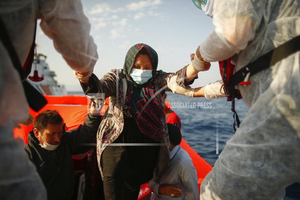 Emrah Gurel Turkish coast guard officers wearing protective gear to help prevent the spread of coronavirus, carry a woman off a life raft during a rescue operation in the Aegean Sea, between Turkey and Greece, Saturday, Sept. 12, 2020. Turkey is accusing Greece of large-scale pushbacks at sea — summary deportations without access to asylum procedures, in violation of international law. The Turkish coast guard says it rescued over 300 migrants "pushed back by Greek elements to Turkish waters" this month alone. Greece denies the allegations and accuses Ankara of weaponizing migrants. (AP Photo/Emrah Gurel)