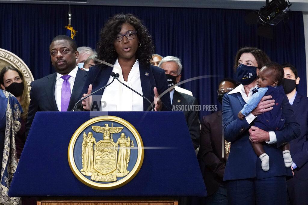 Richard Drew New York state Assembly member Phara Souffrant Forrest speaks, as New York Gov. Kathy Hochul, right, holds her son David, before Hochul signed the "Less is More" law, during ceremonies in the governor's office, in New York, Friday, Sept. 17, 2021. New Yorkers will be able to avoid jail time for most nonviolent parole violations under a new law that will take effect in March, and largely eliminates New York's practice of incarcerating people for technical parole violations. At left is Lt. Gov. Brian Benjamin. (AP Photo/Richard Drew)