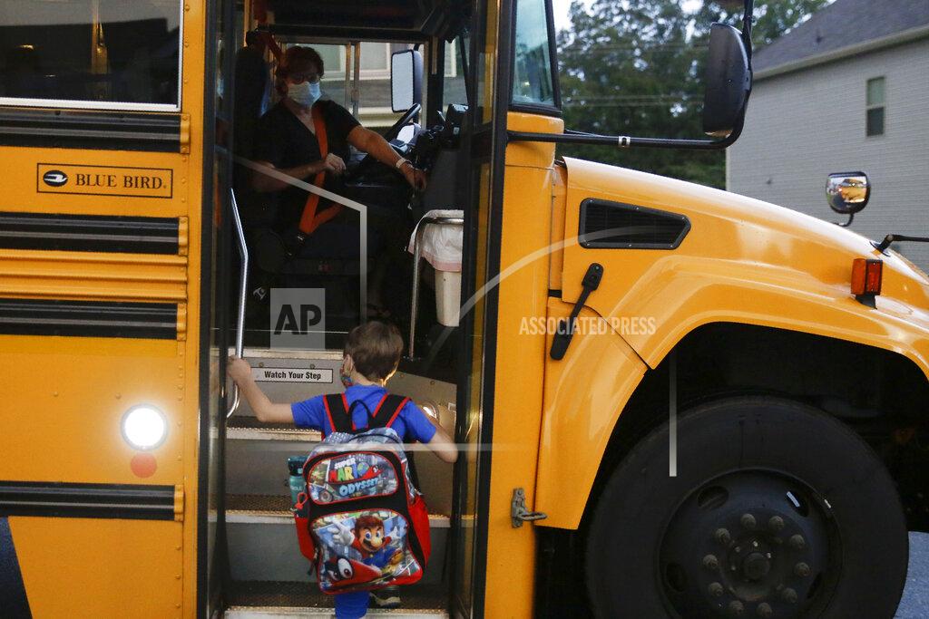 Brynn Anderson Paul Adamus, 7, climbs the stairs of a bus before the fist day of school on Monday, Aug. 3, 2020, in Dallas, Ga. Adamus is among tens of thousands of students in Georgia and across the nation who were set to resume in-person school Monday for the first time since March. (AP Photo/Brynn Anderson)