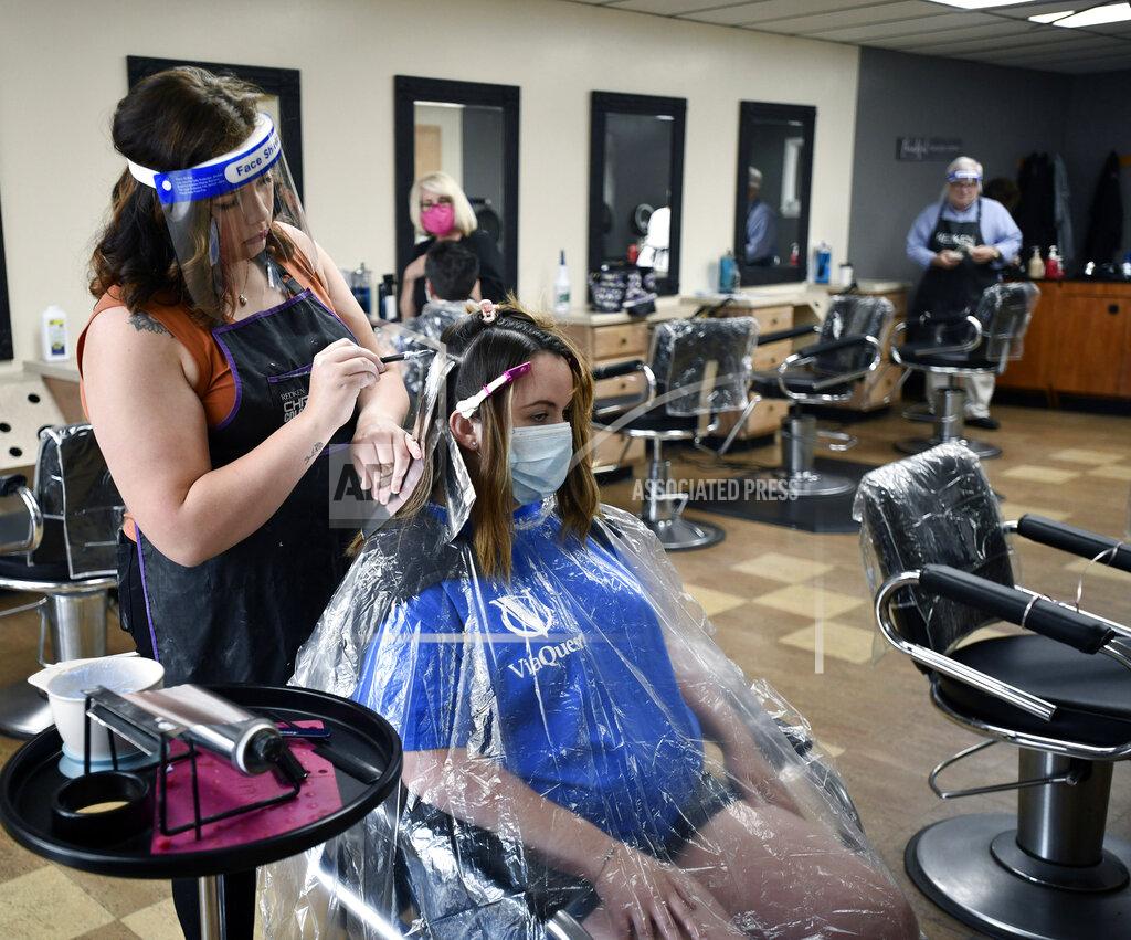 Todd Berkey FILE — In this June 5, 2020 file photo, Salon Vizions stylist Michaela Slayton, left, colors Paulette Fultz hair wearing Personal Protection Equipment, as Fultz wears a mask and disposable gown, in Johnstown, Pa. (Todd Berkey/The Tribune-Democrat via AP)