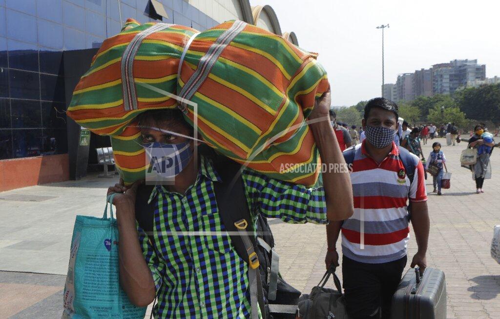 Rajanish Kakade People wearing masks as a precaution against the coronavirus walk to board trains at Lokmanya Tilak Terminus in Mumbai, India, Friday, April 16, 2021. Migrant workers are swarming rail stations in India's financial capital Mumbai to go to their home villages as virus-control measures dry up work in the hard-hit region. The government of Maharashtra state imposed lockdown-like curbs on Wednesday for 15 days to check the spread of the virus. It closed most industries, businesses and public places and limited the movement of people, but didn’t stop the bus, train and air services. An exodus ensued, with panicked day laborers hauling backpacks onto overcrowded trains leaving Mumbai, travel that raises fears of infections spreading in rural areas. (AP Photo/Rajanish Kakade)
