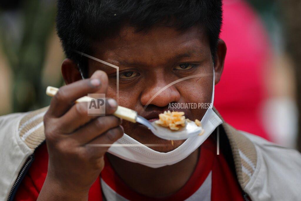 Jorge Saenz Wearing a mask to curb the spread of the new coronavirus, Delio Carballo Martinez, who is unemployed, eats "guiso" at a soup kitchen during a protest by organizations that are feeding the poor, in downtown Asuncion, Paraguay, Monday, Sept.21, 2020. Organizations are demanding that the government begin to provide funds that will help them with their efforts to provide meals for the poor. (AP Photo/Jorge Saenz)