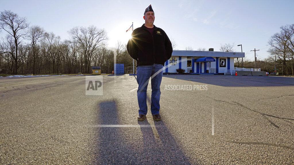 Charles Krupa Craig DeOld, commander at Veterans of Foreign War Post #1018, stands in the post's empty parking lot as the sun sets, Monday, March 15, 2021, in Boston. Local bars and halls run by VFW and American Legion posts have fallen on hard times during the coronavirus pandemic. Organizers say many risk permanent closure after states ordered them, like other bars and halls, to shutter last spring. (AP Photo/Charles Krupa)