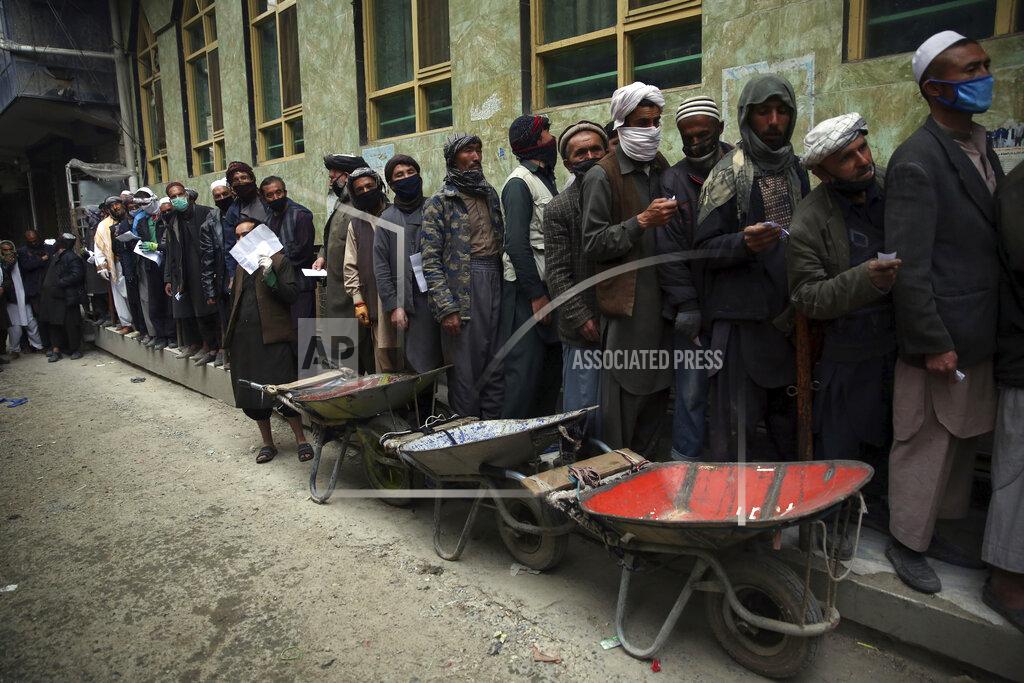 FILE - In this Monday, April 20, 2020 file photo, daily-wage workers wait in line to receive free wheat donated by Afghan businessmen ahead of the upcoming holy fasting month of Ramadan in Kabul, Afghanistan. As Ramadan begins with the new moon later this week, Muslims all around the world are trying to work out how to maintain the many cherished rituals of Islam’s holiest month without further spreading the coronavirus. (AP Photo/Rahmat Gul, File)