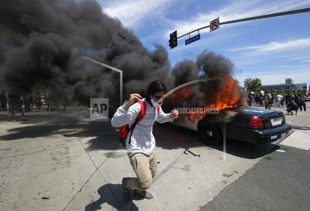 Ringo H.w. Chiu A protester runs while a police vehicle is burning during a protest over the death of George Floyd in Los Angeles, Saturday, May 30, 2020.Protests across the country have escalated over the death of George Floyd who died after being restrained by Minneapolis police officers on Memorial Day, May 25. (AP Photo/Ringo H.W. Chiu)