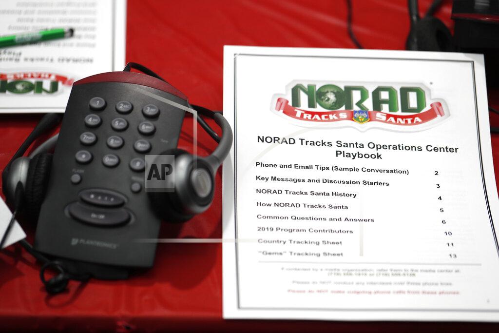 FILE - In this Dec. 23, 2019, file photo a playbook sits next to a telephone set up in the NORAD Tracks Santa center at Peterson Air Force Base in Colorado Springs, Colo. The North American Aerospace Defense Command has announced that NORAD will track Santa on December 24, just as it has done for 65 years. But there will be some changes: Not every child will be able to get through to a volunteer at NORAD’s call center to check on Santa’s whereabouts, as they have in years before. (AP Photo/David Zalubowski, File)