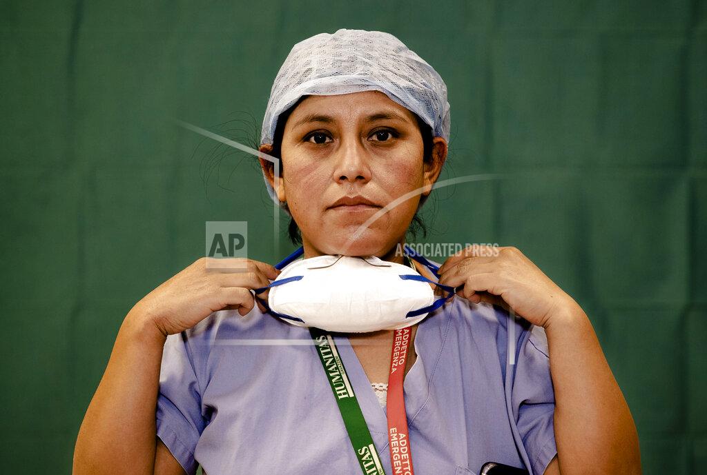 Antonio Calanni Ana Travezano, 39, a nurse at the Humanitas Gavazzeni Hospital in Bergamo, Italy poses for a portrait at the end of her shift Friday, March 27, 2020. The intensive care doctors and nurses on the front lines of the coronavirus pandemic in Italy are almost unrecognizable behind their masks, scrubs, gloves and hairnets. But the thin battle armor donned at the start of each shift is their only barrier to contagion. (AP Photo/Antonio Calanni)