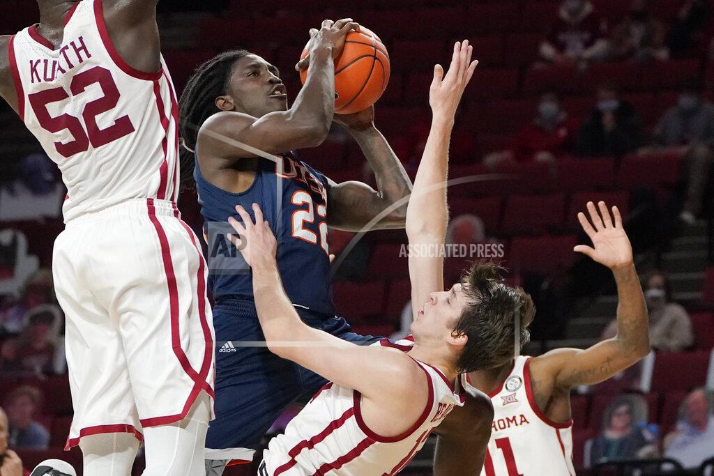 Sue Ogrocki UTSA guard Keaton Wallace (22) commits an offensive foul on Oklahoma guard Austin Reaves, right, as he shoots during the first half of an NCAA college basketball game Thursday, Dec. 3, 2020, in Norman, Okla. (AP Photo/Sue Ogrocki)
