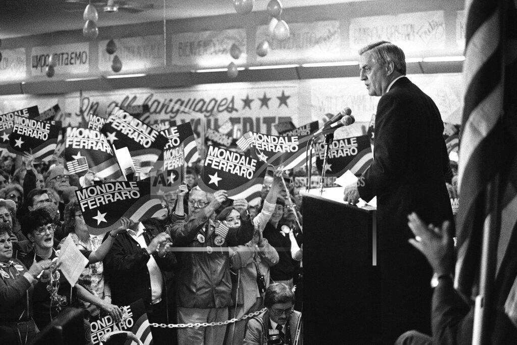 John Duricka FILE - In this Wednesday, Oct. 14, 1984, file photo, a sign-waving crowd cheers Democratic presidential candidate Walter Mondale, right, as he delivers a campaign address at Victory Hall in the Milwaukee suburb of Cudahy, Wis. Campaign workers estimated 1,500 people packed the hall with another 1,000 outside. Mondale, a liberal icon who lost the most lopsided presidential election after bluntly telling voters to expect a tax increase if he won, died Monday, April 19, 2021. He was 93. (AP Photo/John Duricka, File)