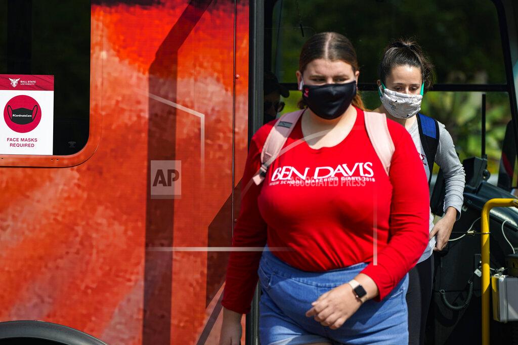 Michael Conroy FILE - Masked students disembark from a bus on the campus of Ball State University in Muncie, Ind., Thursday, Sept. 10, 2020. Colleges across the country are struggling to salvage the fall semester as campus coronavirus cases skyrocket and tensions with local health leaders flare. Schools have locked down dorms, imposed mask mandates, barred student fans from football games and toggled between online and in-person classes. (AP Photo/Michael Conroy)