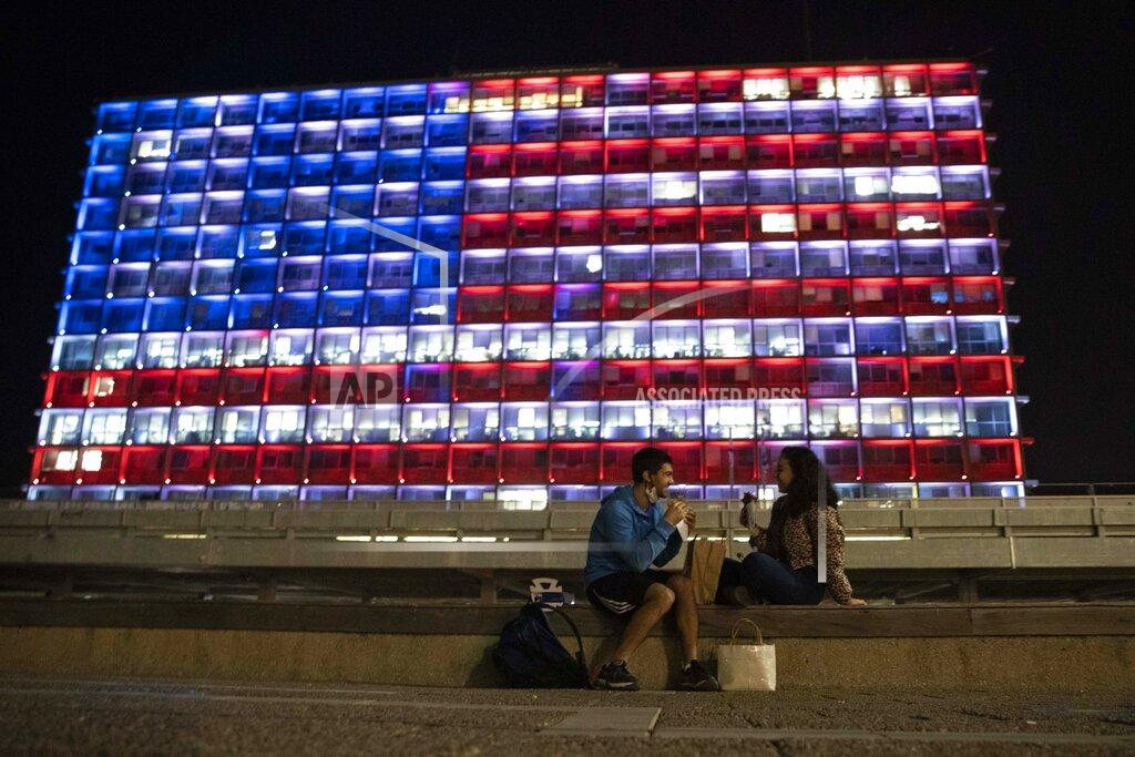 Sebastian Scheiner An Israeli couple sits near the Tel Aviv municipality building as it is lit up with the flag of the United States in Tel Aviv, Israel, Thursday, Jan. 7, 2021. Officials said the display is a sign of solidarity with the United States and support for democracy. (AP Photo/Sebastian Scheiner)