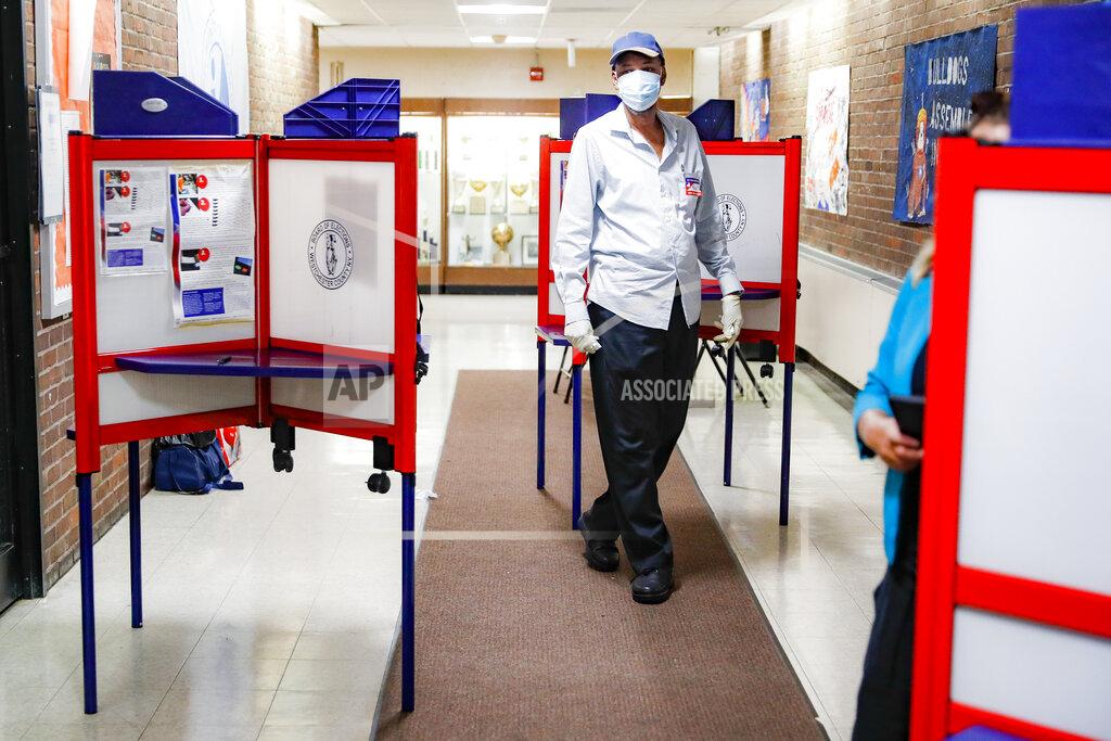 John Minchillo A polling worker walks among voting booths at a voting site inside Yonkers Middle/High School, Tuesday, June 23, 2020, in Yonkers, N.Y. (AP Photo/John Minchillo)