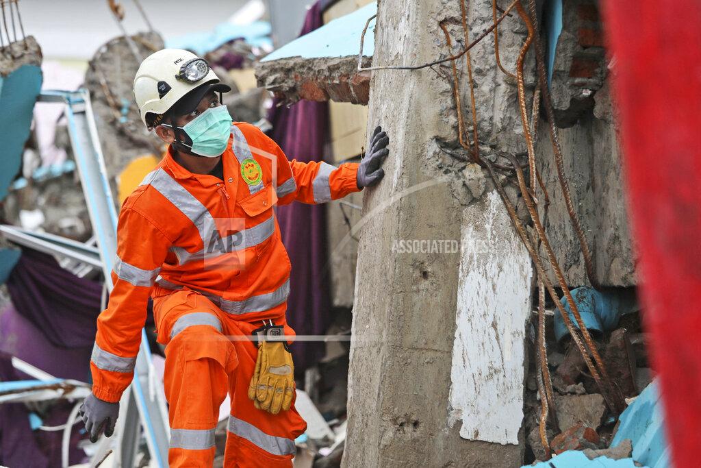 Joshua Marunduh A rescuer inspects the ruin of a building flattened by an earthquake during a search for victims in Mamuju, West Sulawesi, Indonesia, Sunday, Jan. 17, 2021. Rescuers retrieved more bodies from the rubble of homes and buildings toppled by the magnitude 6.2 earthquake while military engineers managed to reopen ruptured roads to clear access for relief goods. (AP Photo/Joshua Marunduh)