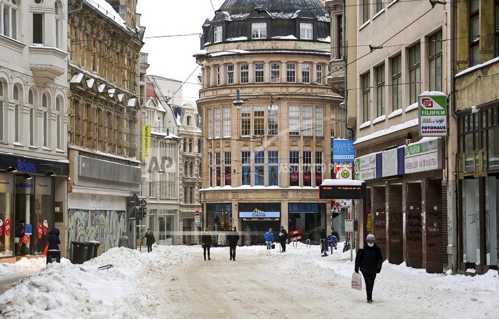 Hendrik Schmidt People walk through the snow covered old town of Halle/Saale, Germany, Friday, Feb. 12, 2021. The winter weather with snow and sub-zero temperatures expected for Germany on the upcoming weekend. (Hendrik Schmidt/dpa via AP)