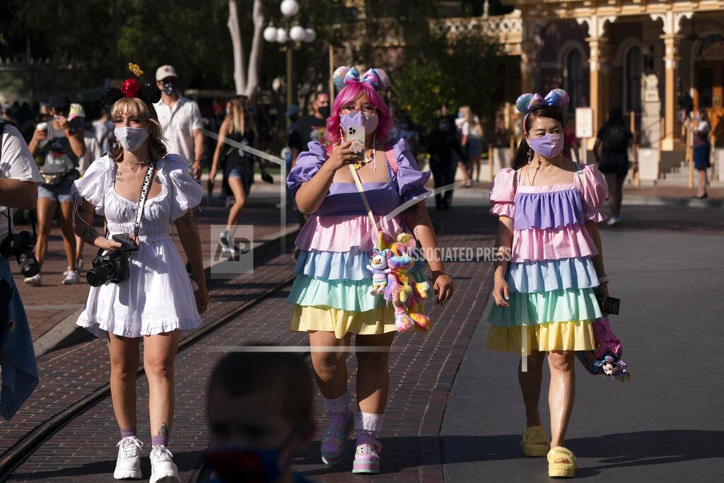 Guests walk along Main Street USA at Disneyland in Anaheim, Calif., Friday, April 30, 2021. The iconic theme park in Southern California that was closed under the state's strict virus rules swung open its gates Friday and some visitors came in cheering and screaming with happiness. (AP Photo/Jae C. Hong)