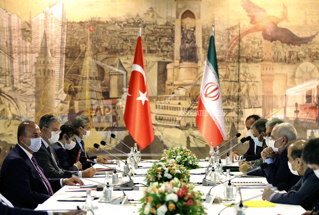 Uncredited Turkish Foreign Minister Mevlut Cavusoglu, left, and Iran's Foreign Minister Mohammad Javad Zarif, second right, wearing face masks to protect against the coronavirus, speak during a meeting, in Istanbul, Monday, June 15, 2020. The two discussed the bilateral issues and Syria. (Turkish Foreign Ministry via AP, Pool)