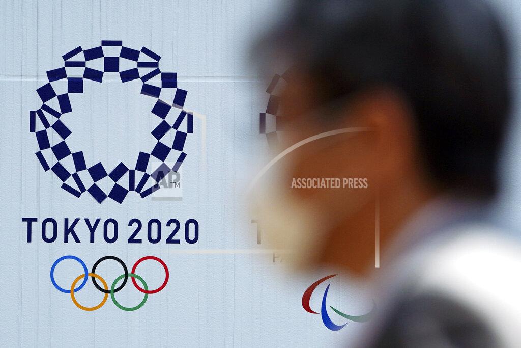 A man wearing a protective face mask walks near the Tokyo 2020 Olympics Thursday, April 2, 2020, in Tokyo. The new coronavirus causes mild or moderate symptoms for most people, but for some, especially older adults and people with existing health problems, it can cause more severe illness or death. (AP Photo/Eugene Hoshiko)