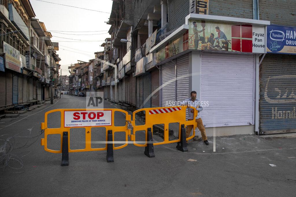 Dar Yasin A Kashmiri man crosses a barricade set up as road blockade by paramilitary soldiers on the first anniversary of India’s decision to revoke the disputed region’s semi-autonomy, in Srinagar, Indian controlled Kashmir, Wednesday, Aug. 5, 2020. Last year on Aug. 5, India’s Hindu-nationalist-led government of Prime Minister Narendra Modi stripped Jammu-Kashmir of its statehood and divided it into two federally governed territories. Late Tuesday, authorities lifted a curfew in Srinagar but said restrictions on public movement, transport and commercial activities would continue because of the coronavirus pandemic. (AP Photo/ Dar Yasin)
