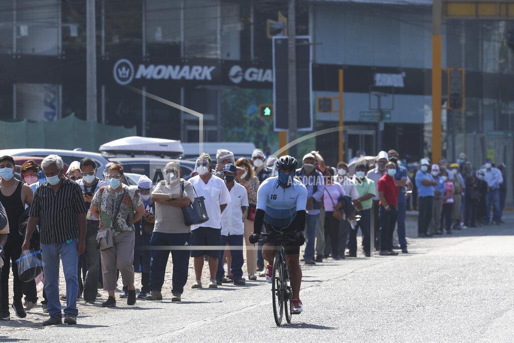 Martin Mejia A cyclist pedals along voters wearing masks to curb the spread of the new coronavirus lining up to enter a polling station during general elections in Lima, Peru, Sunday, April 11, 2021. (AP Photo/Martin Mejia)