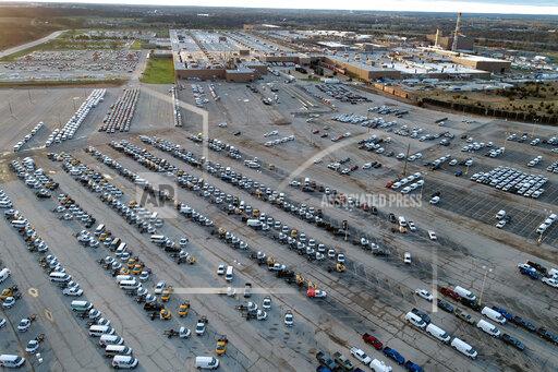 Jeff Roberson In this aerial photo, a General Motors assembly plant is seen at top right while mid-sized pickup trucks and full-size vans currently produced at the plant are seen in a parking lot outside Wednesday, March 24, 2021, in Wentzville, Mo. As the U.S. economy awakens from its pandemic-induced slumber, a vital cog is in short supply: the computer chips that power our cars and other vehicles, and a vast number of other items we take for granted. Ford, GM and Stellantis have started building vehicles without some computers, putting them in storage with plans to retrofit them later. (AP Photo/Jeff Roberson)