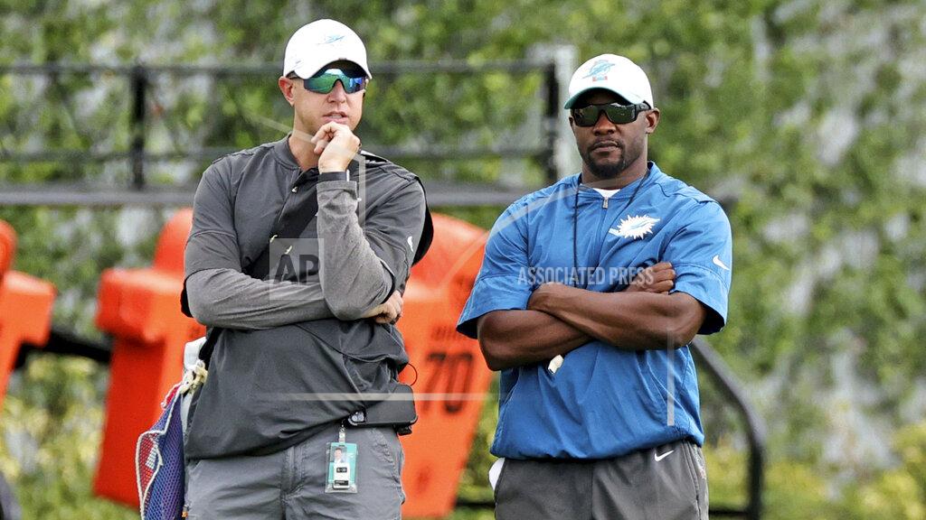 David Santiago Miami Dolphins head athletic trainer Kyle Johnston, left, and Dolphins head coach Brian Flores look on during practice in Miami Gardens Fla., Wednesday, Oct. 13, 2021. The Dolphins play against the Jacksonville Jaguars in London on Sunday. (David Santiago/Miami Herald via AP)