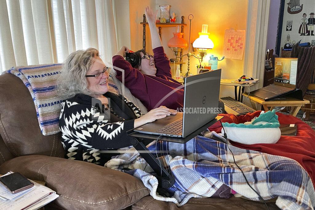 Carolyn Thompson Angelina Mistretta, a 16-year-old junior at City Honors High School shares the couch with her mother Wendy Mistretta, in Buffalo, NY., Feb. 17, 2021. These days, her mother, Wendy, works beside Angelina on the living room couch. (AP Photo/Carolyn Thompson)