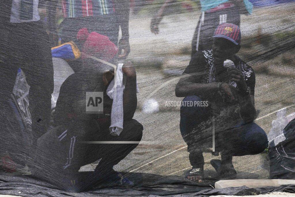 Fernando Vergara Haitian migrants wait behind a cloth separating people who are boarding boats from others waiting their turn in Necocli, Colombia, Monday, Sept. 13, 2021. Migrants have been gathering in Necocli as they move north to Acandi, on Colombia's border with Panama, on their journey to the U.S. border (AP Photo/Fernando Vergara)